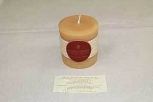 a natural beeswax candle with Honey Candles logo with a candle burning tip sheet laid out in front of it