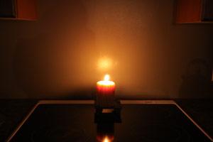 a pure beeswax candle producing a wonder glow while burning on a table in a darkened room