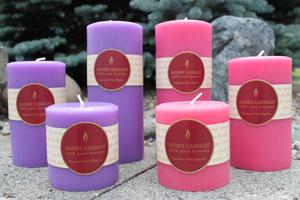 a grouping of purple and pink pure beeswax pillar candles with vibrant Honey Candles logo