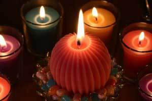 vibrantly colored fluted sphere candle in the center of a ring of many color votive candles all lit and creating an amazing glow and atmosphere