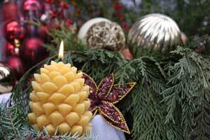 100 percent beeswax pine cone candle in front of a Christmas background