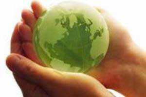 a pair of hands holding a small green globe for Earth Day