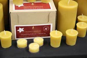 pure beeswax tealight, votive and pillar candles in front of a bulk package with the Honey Candles logo