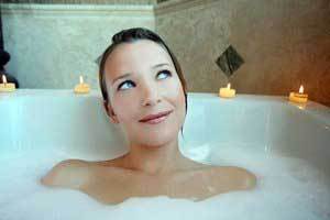 woman in bubble bath with pure beeswax tealight candles on the edge of the tub