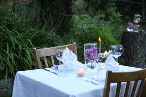beautiful beeswax candles with purple flowers on a white linen dining table for two set up outside