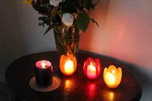 pure beeswax votive candles in flower shaped holders on a end table 