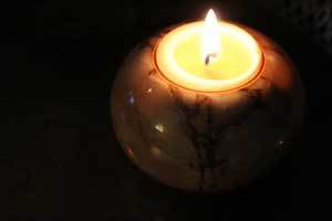 a pure beeswax tealight candle refill burning in a candle holder
