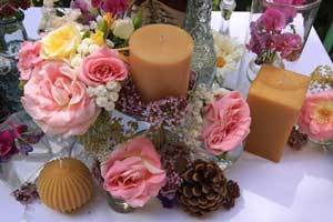 beautiful and sophisticated table setting with pink flowers and natural color beeswax pillar candles and fluted sphere candles