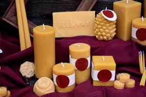 a grouping of natural beeswax candles and blocks of beeswax in different shapes on a burgundy cloth