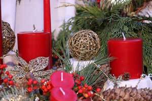 red pure beeswax pillar candle and votive candles in a holiday setting including pine cone