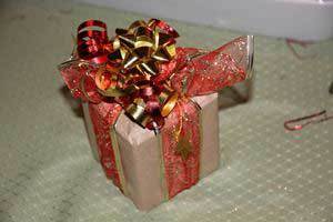 a Christmas gift packaged in brown paper and trimmed with a large red and gold bow and ribbon