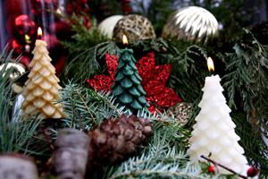 pure beeswax tree candles in white, brown and green nestled in a Christmas centerpiece of greenery and silver tree ornaments