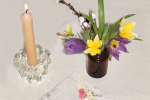 pure beeswax candlestick burning next to a bouquet of purple and yellow flowers