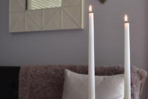 two white pure beeswax taper candles in a black candle holder