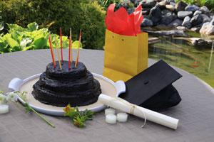 pure beeswax gala candles in a chocolate graduation cake next to a graduation cap and diploma