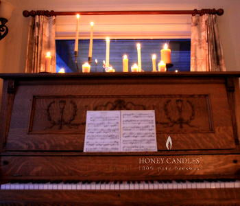 multiple pure beeswax candles burning on the top of a piano