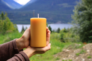pure beeswax pillar candle in front of a mountain setting