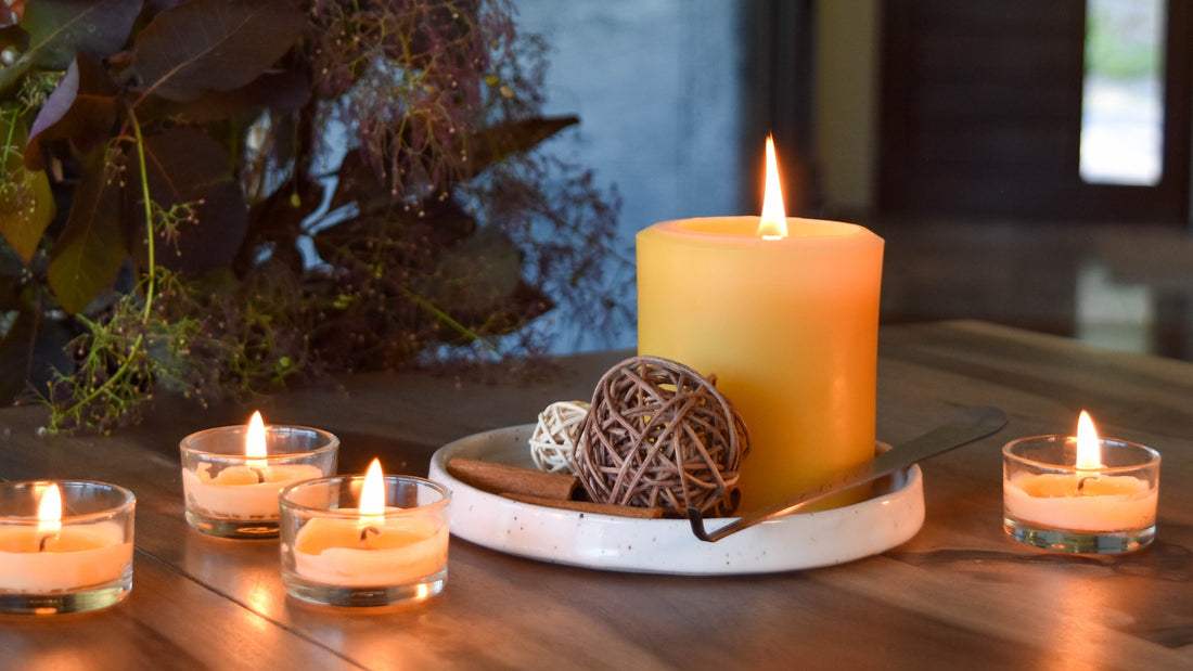 Beeswax tealights burning on a table around a beeswax pillar with fall decor.