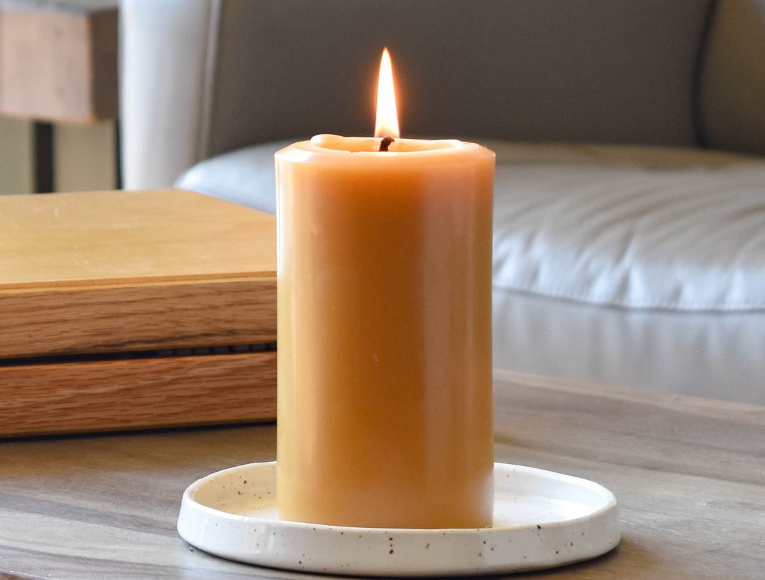 A beeswax pillar candle in a clean kitchen with bright summer flowers