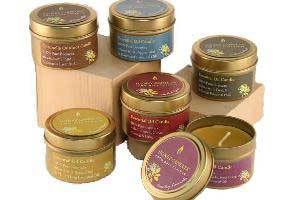 a grouping of pure beeswax essential candles in metal tins with colorful labels