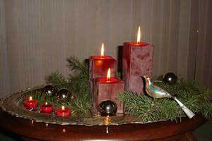 a group of red beeswax pillar candles and tealight candles on a silver tray with greenery perfect for holiday decoration