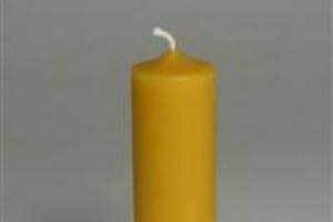 a simple pure beeswax column candle set in front of a grey background