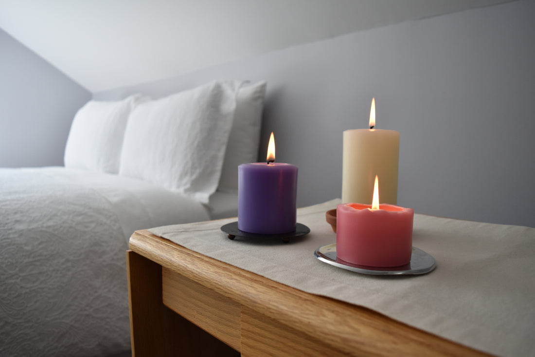 Purple, white and pink pure beeswax candles in a bedroom setting