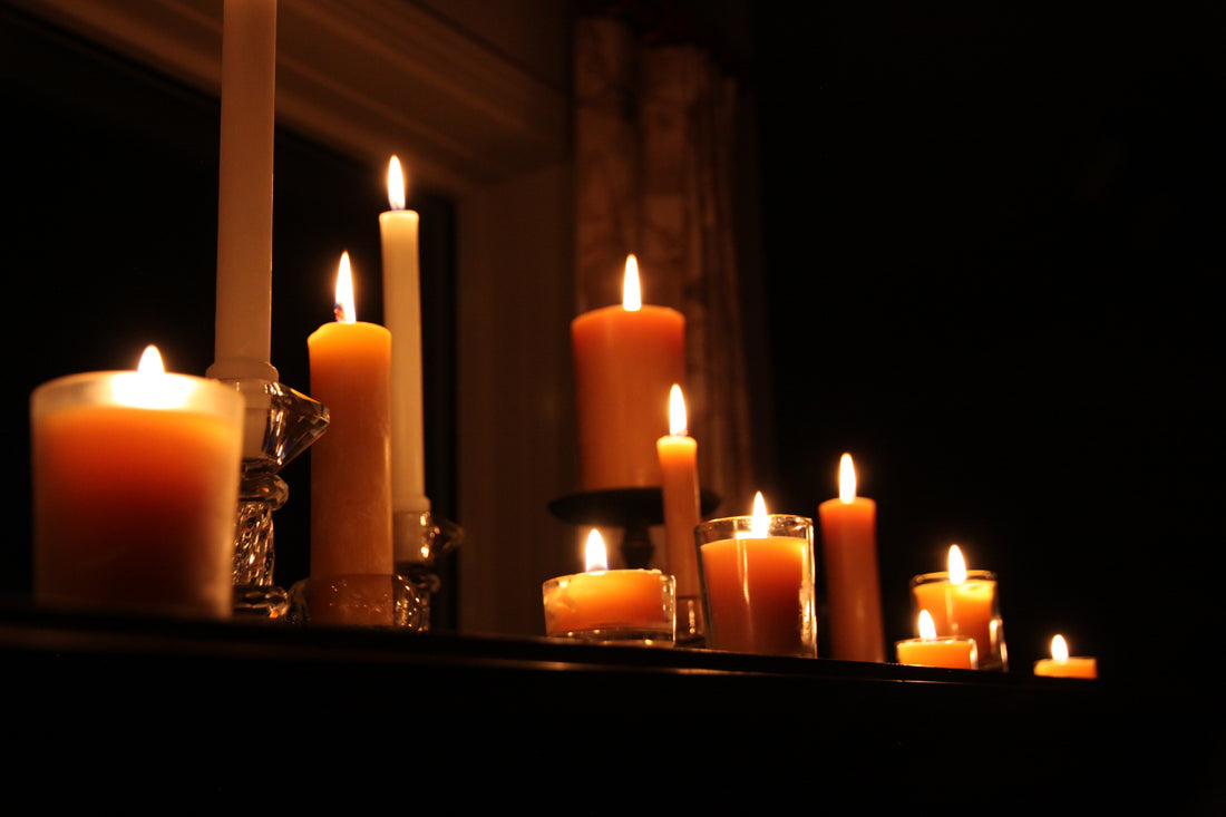 a variety of beeswax candles burning in a dark room 