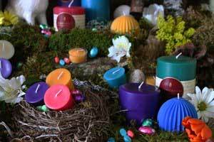 a nest adorned with pure beeswax candles in a rainbow of colors like blue, pink, purple and teal