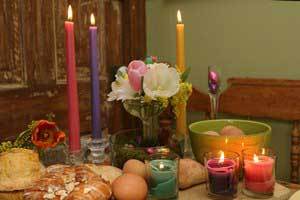dining table set with pure beeswax candlesticks and votive candles in purple, pick, and teal