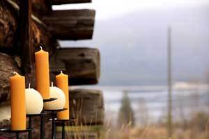 pure beeswax column and sphere candles on rod iron candle holders near an old barn