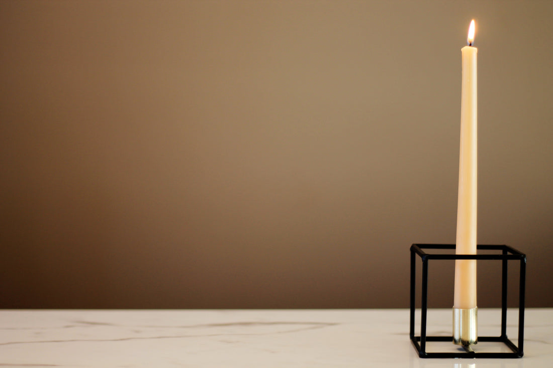 Elegant beeswax taper candlestick in a simple candle holder