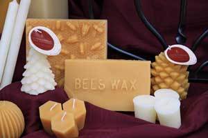 Real Beeswax Candles and blocks of wax in natural and pearl white color on a burgundy cloth