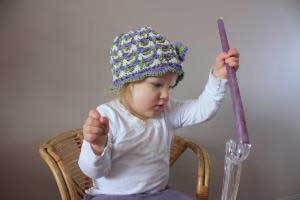 a young child holding a purple beeswax candlestick and trying to put it in a candle holder