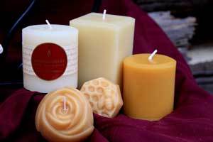 beautiful grouping of round pillar, square pillar, and rose beeswax candles on red blanket