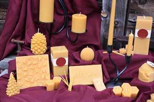 pure beeswax pillar candles, pine cone candles, beeswax blocks and candlesticks on a red sheet