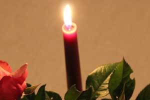 a red beeswax candlestick with a lovely flame surrounded by roses