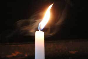 a paraffin candle shown with the flame causing dripping on the candle and the table