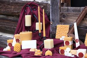 a grouping of Honey Candles pure beeswax natural candles on a burgundy sheet by a barn door