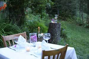 dining table outside in the yard set with pure beeswax candles and crisp white linens and purple flowers