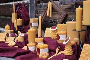 large grouping of natural colored pure beeswax candles in many shapes and sizes on a burgundy blanket