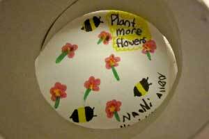 kids artwork that says Plant more flowers and has painted bees and flowers on it