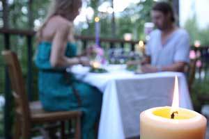 pure beeswax candle burning as a couple are having dinner on a restaurant patio
