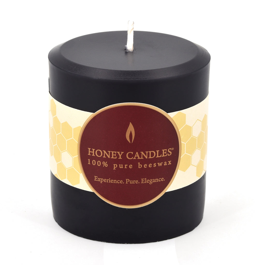 A Honey Candles Black beeswax candle in a classic pillar shape