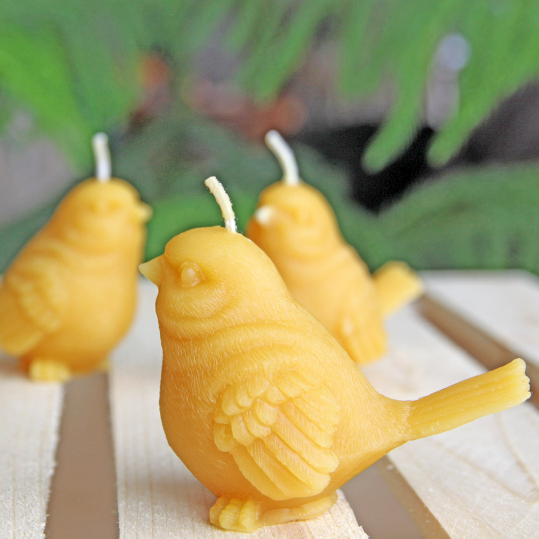 Group of three ornate beeswax bird candles on wooden crate